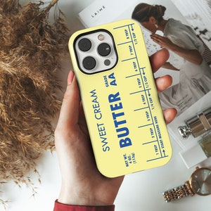 May include: A yellow phone case with a blue and white label that reads "Sweet Cream Butter AA" and includes a measurement guide for tablespoons and cups. The case is designed to look like a stick of butter.