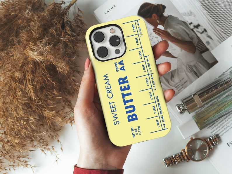May include: A yellow phone case with a blue and white label that reads "Sweet Cream Butter AA" and includes a measurement guide for tablespoons and cups. The case is designed to look like a stick of butter.