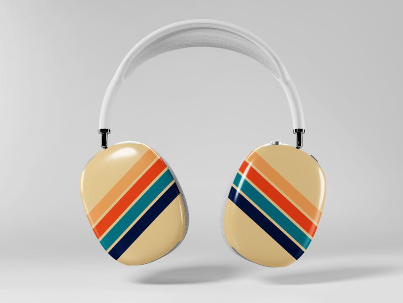 May include: Cream-colored over-ear headphones with a white headband. The earcups feature a retro design with diagonal stripes in orange, red, teal, and navy blue. The headphones are suspended in the air against a plain background.