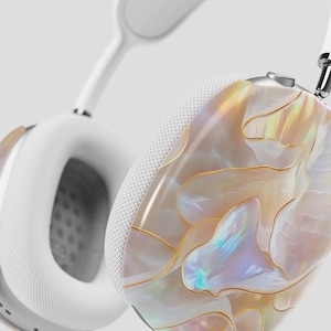 May include: White headphones with a pearlescent shell design on one earcup. The shell design features a swirling pattern of white, gold, and iridescent colors.