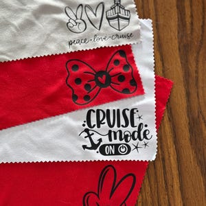 May include: Four white microfiber cloths with black printed designs. The designs include a peace sign, heart, cruise ship, bow with polka dots, anchor, power button, and Mickey Mouse hand. The text on the cloths reads "peace.love.cruise" and "cruise mode on".