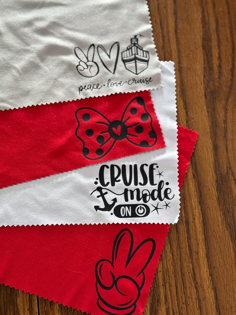 May include: Four white microfiber cloths with black printed designs. The designs include a peace sign, heart, cruise ship, bow with polka dots, anchor, power button, and Mickey Mouse hand. The text on the cloths reads "peace.love.cruise" and "cruise mode on".