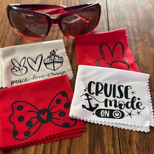 May include: Four red and white microfiber cleaning cloths with different designs. The designs include a peace sign, a heart, a cruise ship, a bow, Mickey Mouse ears, and an anchor with the text "Cruise Mode On".