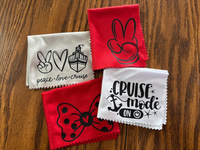 May include: Four white microfiber cloths with black printed designs. The designs include a peace sign, a heart, a cruise ship, a bow with polka dots, an anchor, and the text "cruise mode on".