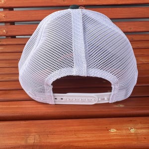 Pu&ograve; includere: Cappellino da baseball in rete bianca con visiera nera e cinturino regolabile bianco. La parte posteriore del cappello &egrave; realizzata in rete traspirante.