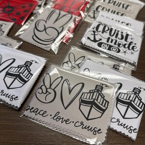 May include: A variety of microfiber cleaning cloths with different designs. The cloths feature peace signs, hearts, cruise ships, and the text "Peace. Love. Cruise" and "Cruise Mode On".