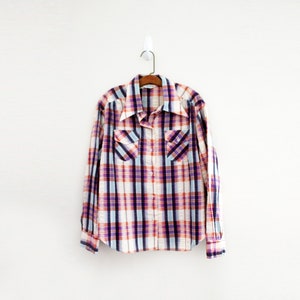 May include: A plaid shirt with a white background and red, blue, and purple checks. The shirt has a button-down collar and long sleeves.