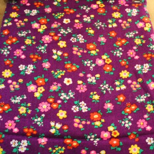 May include: Purple fabric with a repeating pattern of small pink, yellow, and orange flowers.