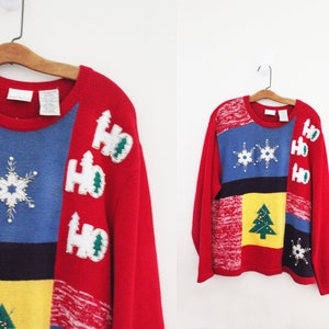 May include: A red, blue, yellow, and white Christmas sweater with a patchwork design. The sweater has snowflakes, Christmas trees, and "Ho Ho Ho" written on it.