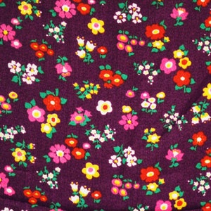 May include: Purple fabric with a repeating pattern of small pink, yellow, and red flowers.
