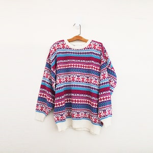 May include: A white, blue, pink, and purple patterned sweater with a crew neck.