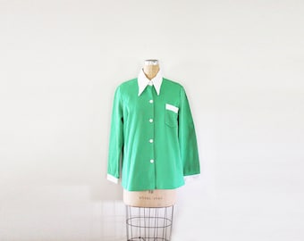 May include: A green and white checkered long-sleeve shirt with a white collar and a white pocket on the left side.