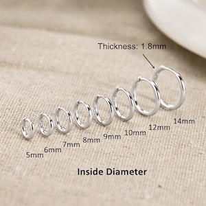 May include: A set of eight silver-toned hoop earrings arranged in a row by size. The earrings range from 5mm to 14mm in inside diameter, with a labelled thickness of 1.8mm. The text labels indicate the inside diameter for each individual hoop.