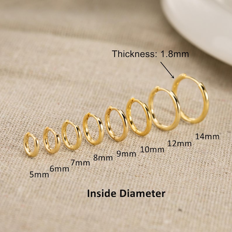 May include: A set of seven gold hoop earrings arranged in increasing size from 5mm to 14mm in inside diameter. Each hoop has a thickness of 1.8mm. The text labels indicate the specific inside diameter for each earring in the sequence.