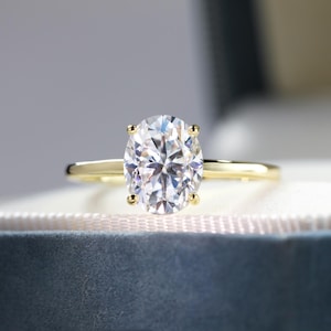 Könnte beinhalten: Ein goldener Verlobungsring mit einem großen ovalen Diamanten.