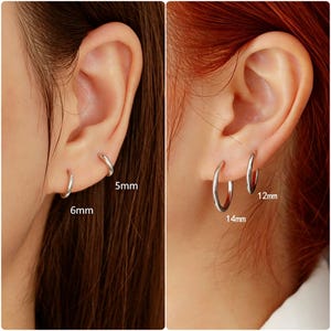 May include: A set of four silver-toned hoop earrings in varying sizes. The earrings are labelled with their respective diameters: 5mm, 6mm, 12mm, and 14mm. These circular metal hoops feature a smooth, polished finish and a simple, continuous design.