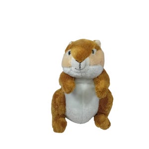 Puede incluir: Un peluche de ardilla con pelaje marrón y canela, vientre blanco y una pequeña nariz y boca cosidas en negro. El animal de peluche está sentado erguido con los brazos y las piernas extendidos.