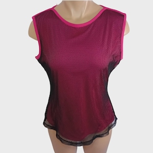 May include: A sleeveless top with a mesh overlay. The top is primarily a deep magenta color, with black mesh accents on the sides and bottom. The neckline and armholes are trimmed with a bright pink fabric.