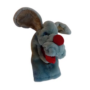 May include: A blue and brown plush hand puppet with a red nose and tongue. The puppet is shaped like a dog with large ears.