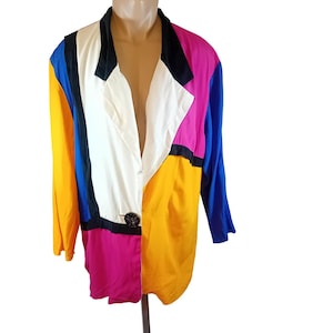 Peut inclure: Un blazer à manches longues présentant un design color-block audacieux en jaune vif, rose éclatant, bleu roi, blanc et noir. Le vêtement possède un revers cranté, une fermeture à un seul bouton circulaire foncé à la taille et une silhouette structurée.