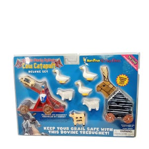 Può includere: Un set Monty Python and the Holy Grail Cow Catapult Deluxe nella confezione originale. Include una catapulta in plastica rossa, un trabucco in stile legno, due anatre bianche, due pecore bianche, una mucca maculata e un proiettile a forma di mucca.
