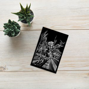 May include: A black and white drawing of a building with trees and a street in front of it. The drawing is done in a scratchboard style, with white lines on a black background.