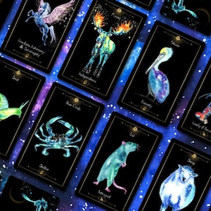 May include: A collection of tarot cards with watercolor illustrations of animals and celestial elements. Each card features a different animal, such as a snail, crab, and rat, with a corresponding word or phrase. The cards have a black background with gold borders.