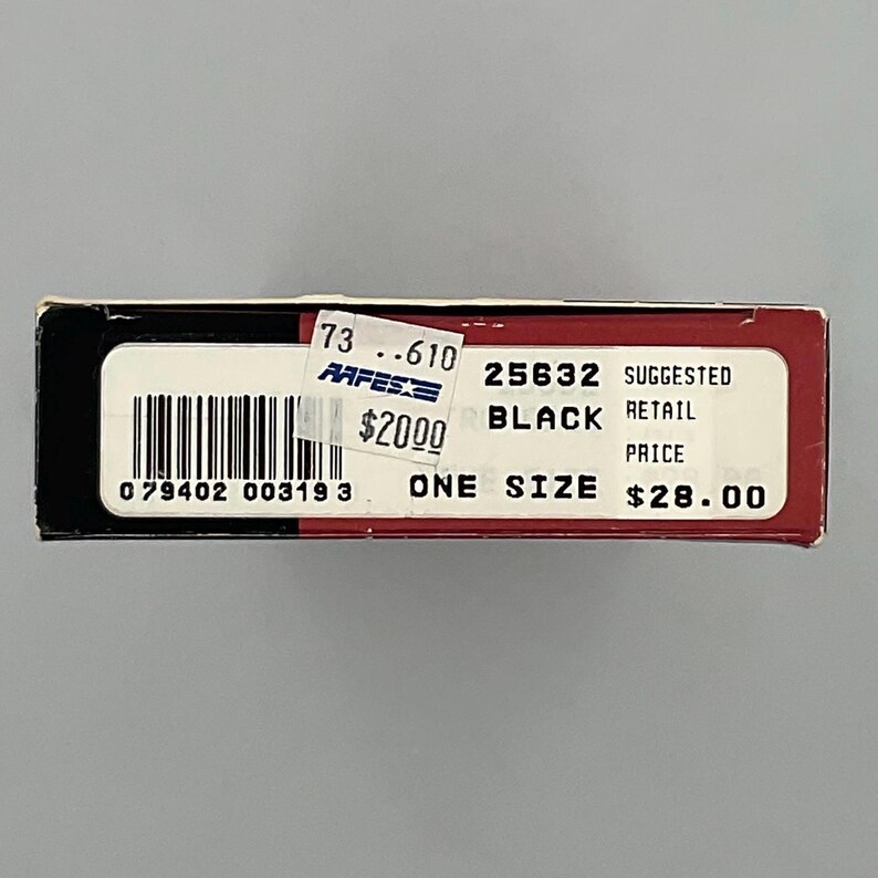May include: A rectangular product box with a black and red exterior. The white label features a barcode, the text 25632, BLACK, ONE SIZE, and SUGGESTED RETAIL PRICE $28.00. A small sticker displays 73 .610, AAFES, and $20.00 over the barcode area.