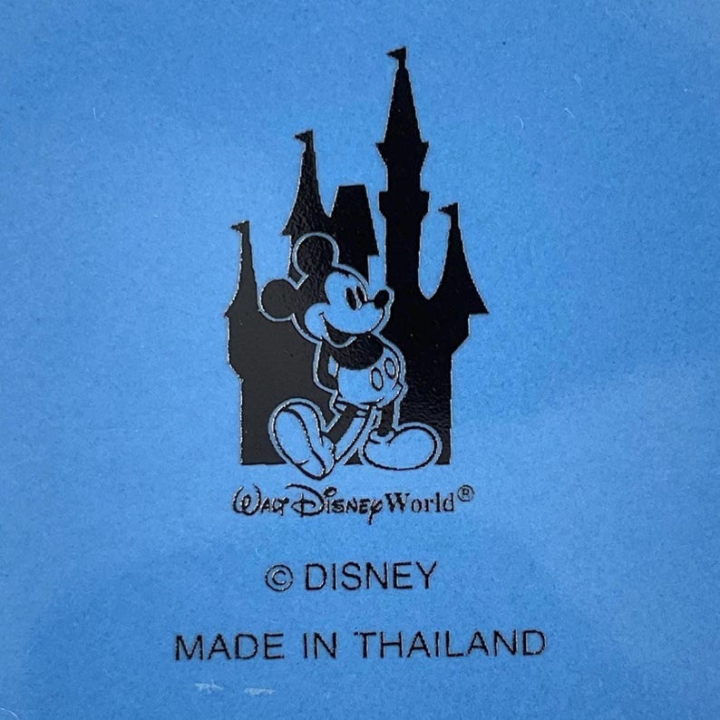 May include: A light blue background features a black silhouette of a castle and Mickey Mouse. The text "Walt Disney World", "&copy; Disney", and "MADE IN THAILAND" are also visible.