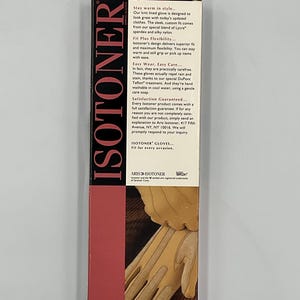 May include: A rectangular Isotoner product box featuring a vertical red panel with the brand name in white text. The box includes descriptive text about knit-lined gloves and a graphic showing tan gloves being worn on a dark brown surface.