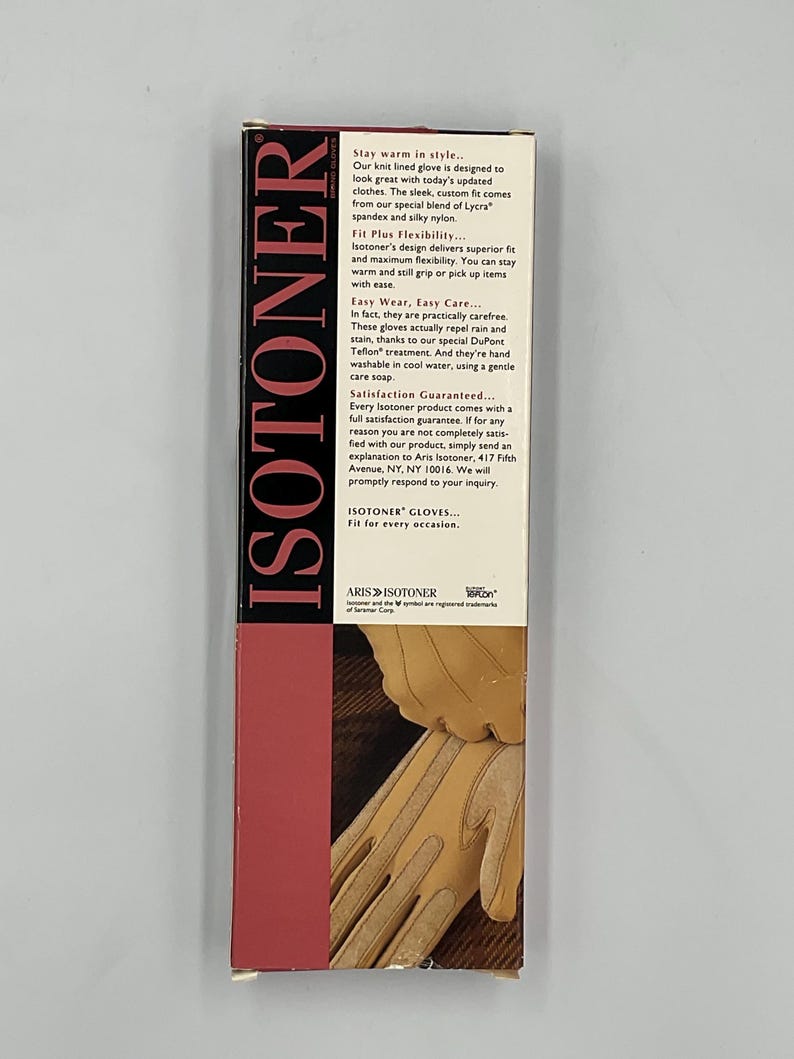 May include: A rectangular Isotoner product box featuring a vertical red panel with the brand name in white text. The box includes descriptive text about knit-lined gloves and a graphic showing tan gloves being worn on a dark brown surface.