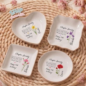May include: Four white ceramic trinket dishes in heart, square, and round shapes. Each dish features the text Chapter Seventy, Happy 70th Birthday, and a name with a floral illustration. The dishes are decorated with a yellow daffodil, purple violets, pink carnations, and a red rose.