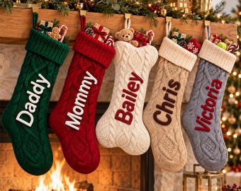 May include: Five cable-knit Christmas stockings hanging in a row. The green stocking says Daddy, the red says Mommy, the cream bone-shaped one says Bailey, the tan says Chris, and the gray says Victoria. Each stocking is filled with small gifts.