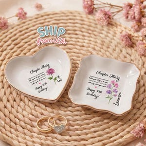 May include: Two white ceramic trinket dishes with gold-toned rims, one heart-shaped and one square with wavy edges. Both feature floral illustrations, the text Chapter Thirty, Happy 30th Birthday, and personalized names Evie and Lauren.