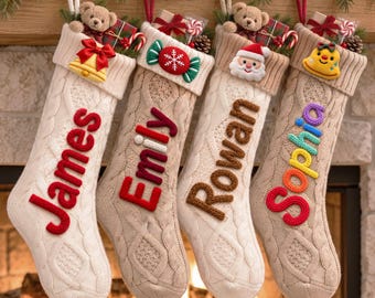 May include: Four cream-colored cable knit Christmas stockings hanging in a row. Each stocking features a plush toy, a small gift box, and a unique felt ornament on the cuff. The names James, Emily, Rowan, and Sophia are embroidered in large, colorful yarn letters.