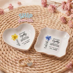 May include: Two white ceramic trinket dishes, one heart-shaped and one square with scalloped edges, both featuring floral illustrations and text reading Chapter Eighty, Eloise or Tabitha, and Happy 80th Birthday, Love, Micah or Juliette.