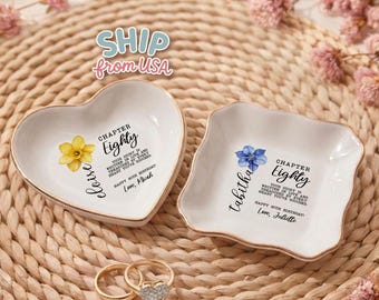 May include: Two white ceramic trinket dishes, one heart-shaped and one square with scalloped edges, both featuring floral illustrations and text reading Chapter Eighty, Eloise or Tabitha, and Happy 80th Birthday, Love, Micah or Juliette.