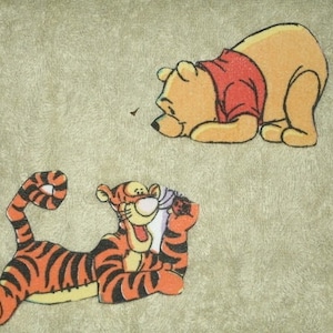 May include: A brown bear with a red shirt and a tiger with orange and black stripes. The bear is lying on its stomach with its head turned to the side. The tiger is lying on its side with its head turned to the side. Both characters are from the Winnie the Pooh franchise.