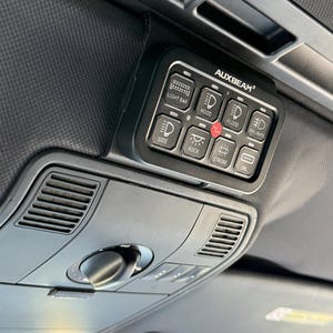 May include: A black AUXBEAM switch panel with eight buttons for controlling lights. The buttons are labeled "Light Bar", "Hood", "Flood", "Fog Lights", "Side", "Rock", "Strobe", and "Ctrl".