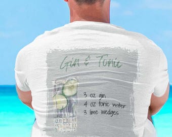 May include: White t-shirt with a Gin & Tonic recipe graphic. The graphic includes a drawing of a cocktail with cucumber slices and the ingredients: 3 oz gin, 4 oz tonic water, and 3 lime wedges. The shirt is worn by a person.