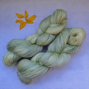 Pode incluir: Um novelo de fio verde claro, torcido e dobrado, sobre uma superf&iacute;cie branca.