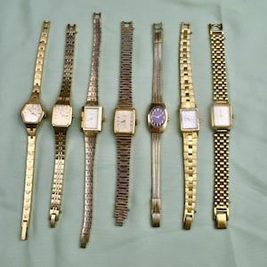 May include: A collection of seven vintage gold-toned wristwatches with various band styles and face shapes. The watches feature rectangular, square, and oval faces with different dial designs. The bands include link, mesh, and chain styles, showcasing a range of classic watch designs.