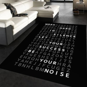 May include: Black and white rug with the words "Work Hard In Silence Let Your Success Be Your Noise" written in a vertical column.