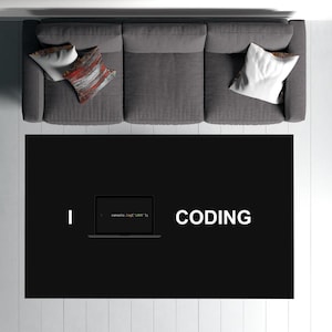 Puede incluir: Una alfombra en blanco y negro con el texto "I CODE" y "CODING" en ella. Una computadora portátil con el código "console.log('LOVE');" se muestra en la alfombra.