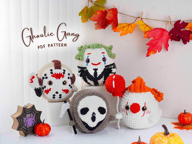 May include: A collection of handmade crochet Halloween characters, including a Jason Voorhees, a Joker, a Grim Reaper, and a clown holding a red balloon. The text "Ghoulie Gang PDF Pattern" is displayed above the characters. Decorative pumpkins and fall leaves are also present.