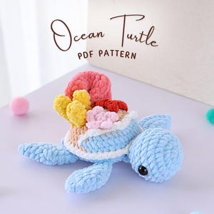 May include: A crocheted ocean turtle toy with a blue body and a shell decorated with colorful coral. The toy is made with soft yarn and has a sweet expression.