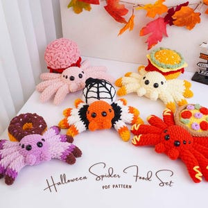 May include: A collection of five crocheted spiders paired with food items including a pink spider with a brain, a yellow spider with a burger, a white and orange spider with a web, a purple spider with a donut, and a red spider with a pizza.