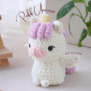 Könnte beinhalten: Ein weißes gehäkeltes Einhorn mit einer lila Mähne und einem gelben Horn. Das Einhorn hat eine rosa Nase und schwarze Augen. Der Text "Puff Unicorn" ist in Braun über dem Einhorn geschrieben. Der Text "PDF PATTERN" ist in Braun unter dem Einhorn geschrieben.