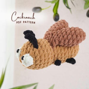 May include: A handmade, plush cockroach toy in shades of brown, tan, black, and white. The text "Cockroach PDF Pattern" is visible in the upper left corner. The toy is made of a soft, textured material, with a detailed design.