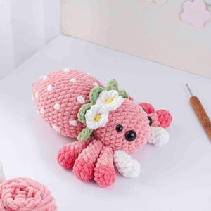 May include: A handmade pink crochet octopus with white polka dots, black eyes, and a floral headband. The octopus has eight tentacles with white tips and is a soft, plush toy.